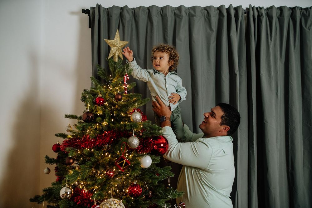 Pai a ajudar o filho a colocar a estrela no topo da árvore de Natal